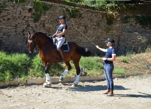 Casal amazona-cavalo lusitano e a treinadora, trabalho do piaffe